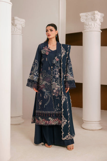 A woman modeling a dark navy blue embroidered traditional outfit with matching pants, standing between white classical columns in an indoor architectural setting.